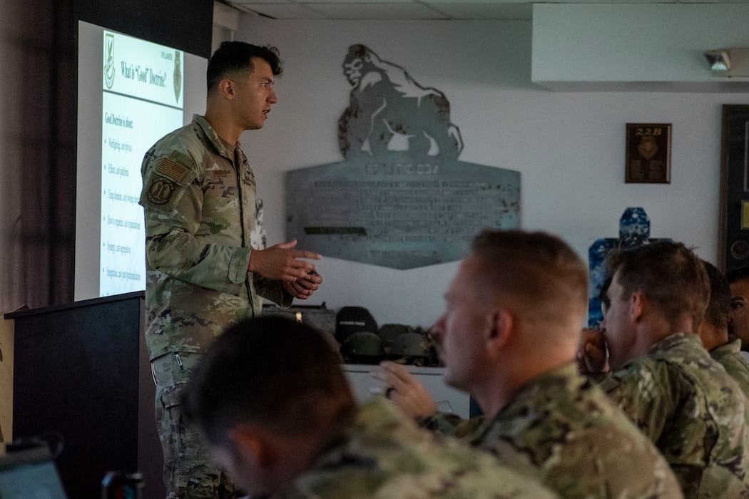 instructor standing at left with row of students sitting in front of him