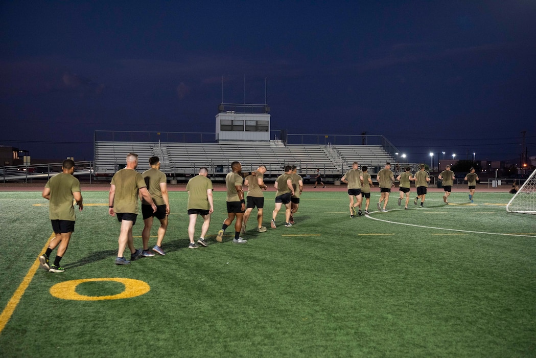 students run off a football field in PT gear