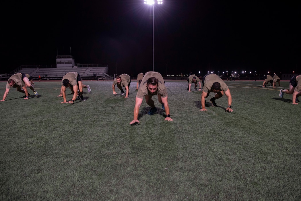 students perform exercises on a football field