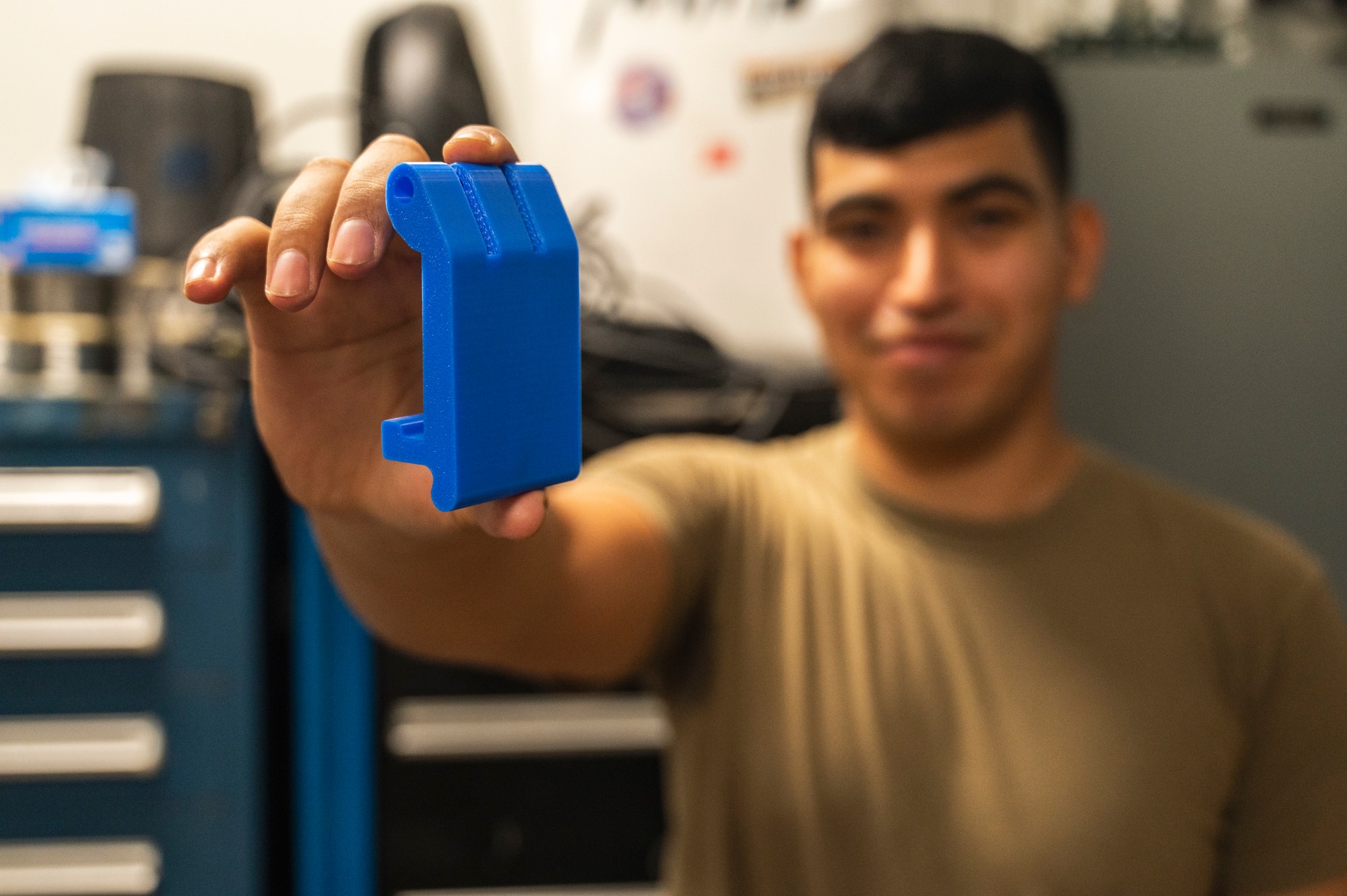 Senior Airman Pedro Garay, 35th Fighter Generation Squadron crew chief, holds up a 3D printed pelican case latch
