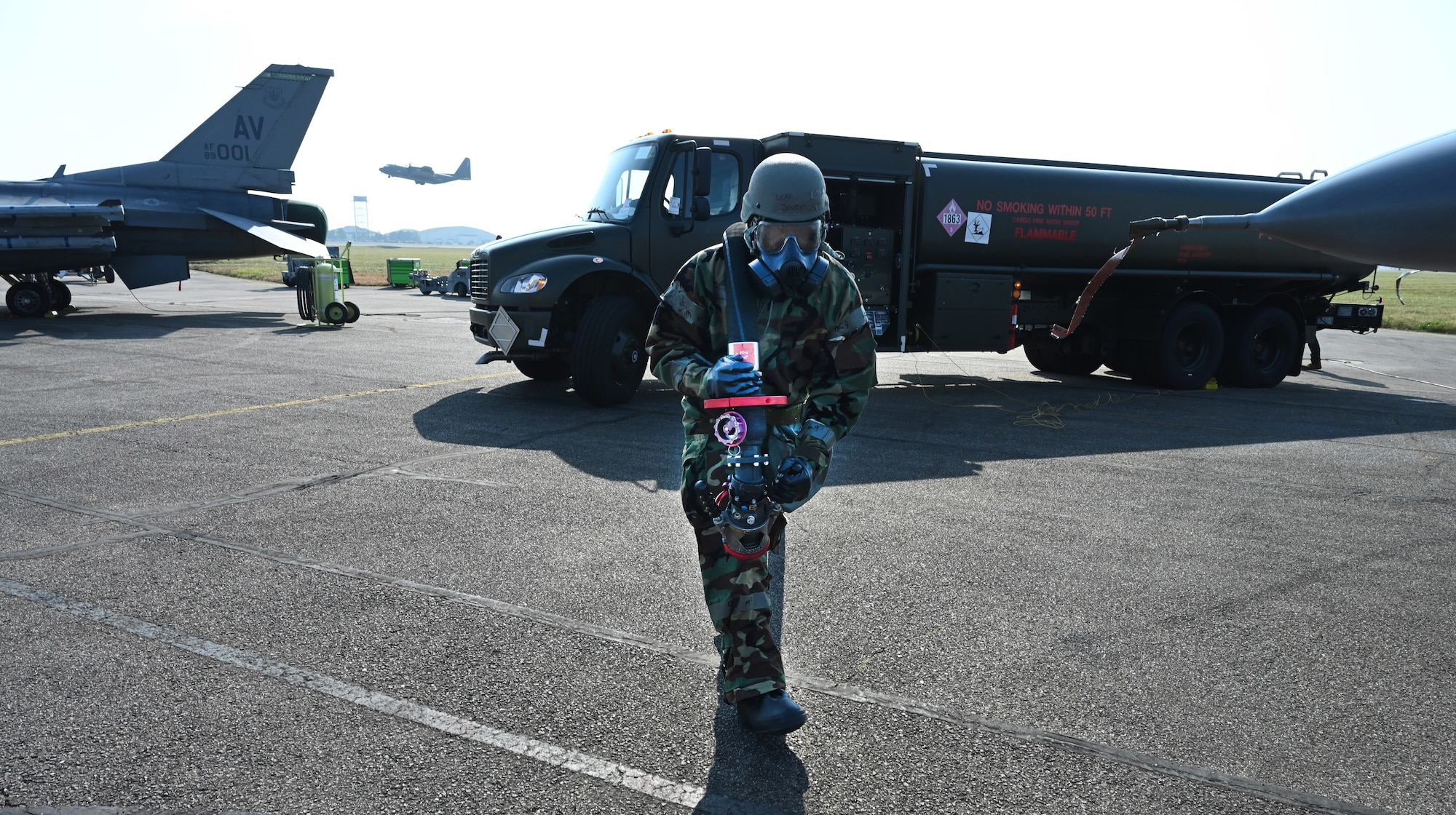 U.S. Air Force Senior Airman Jovon Green, 100th Logistics Readiness Squadron Petroleum, Oils and Lubricants flight fuels distribution technician, pulls a hose from an R-11 Refueler truck over to F-16 Fighting Falcons from Aviano Air Base, Italy, while wearing mission-oriented protective posture gear at Royal Air Force Mildenhall, England, Sept. 19, 2024. RAF Mildenhall hosted the aircraft for Cobra Warrior 24-2 – a UK RAF-sponsored exercise – and chose to test their chemical, biological, radiological and nuclear support capabilities for the multi-lateral, live-fly field-training exercise. (U.S. Air Force photo by Karen Abeyasekere)