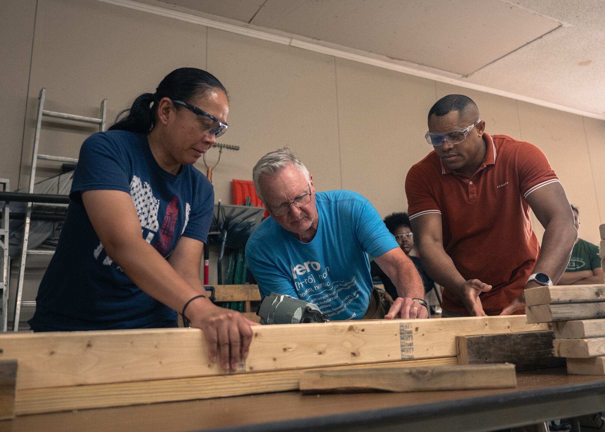 3 people nail wood together.