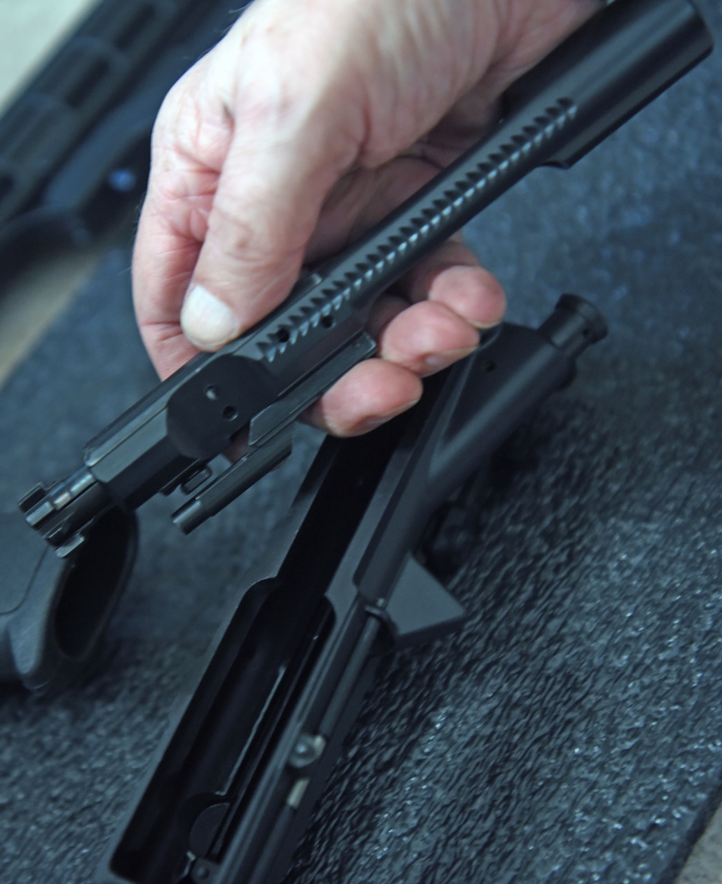 A bolt carrier group is removed from a rifle.