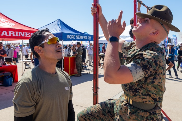 U.S. Marine Corps Sgt. Michael Pocrnich, a drill instructor with Delta Company, 1st Battalion, Marine Corps Recruit Depot San Diego, encourages an expo attendee participating in a pull-up challenge during the 2024 Marine Corps Air Station Miramar Airshow at MCAS Miramar in San Diego, Sept. 28, 2024. The MCAS Miramar Airshow provides a unique flightline experience with static displays and daytime shows that feature military demonstration teams, civilian acrobatic teams, aerial solo acts, vintage aircraft and warbirds. (U.S. Marine Corps photo by Cpl. Bruin Largent)