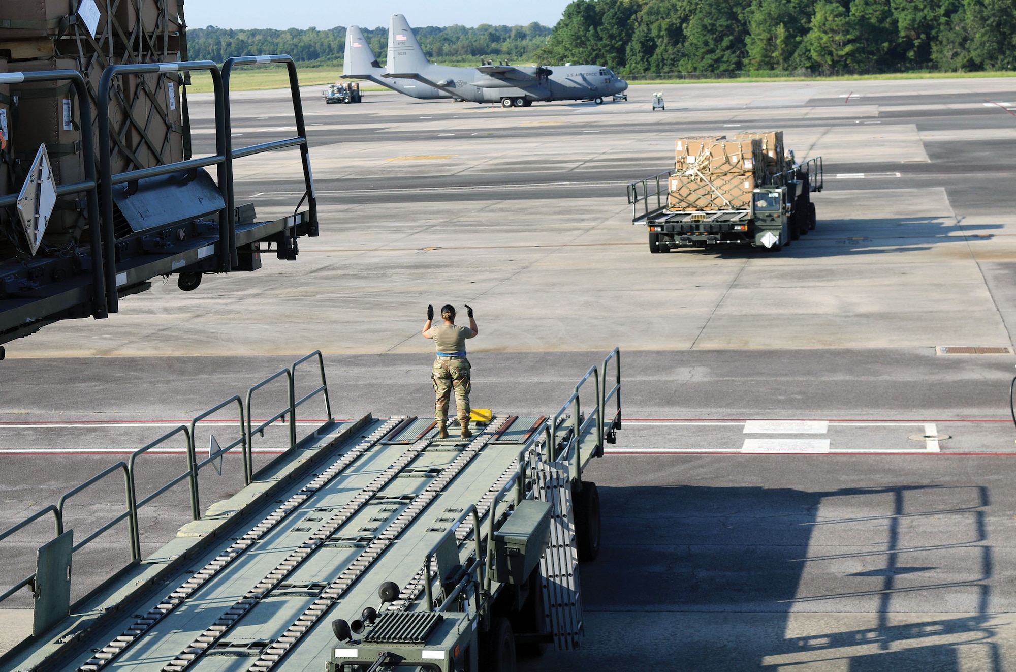 Senior Airman Georzena Sumang, 87th Aerial Port Squadron cargo representative, spots a Tunner 60K Loader into place as part of a cargo loading operation at Joint Base Charleston, S.C., Aug. 15, 2024. Airmen from the 87th APS and 437th APS staged cargo on three loaders assembled as a bridge and elevator.