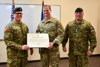 From left, Maj. Gen. John Errington, commander of the Canadian Army Doctrine and Training Centre; U.S. Air Force Lt. Col. Kevin Thomas, commander of the 284th Air Support Operations Squadron; and Chief Warrant Officer Pascal Gagne, Sergeant Major of the Canadian Army Doctrine and Training Centre, hold the scroll element of the Canadian Forces Unit Commendation award during a ceremony at Smoky Hill Air National Guard Range, Kansas, Oct. 1, 2024.