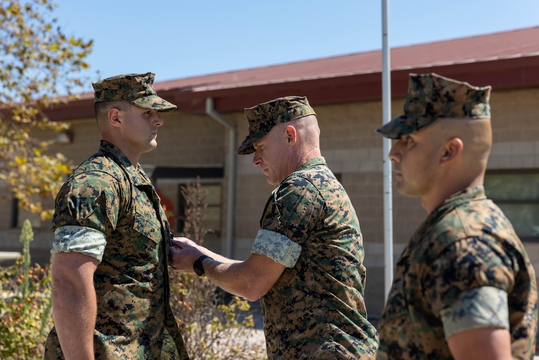 U.S. Marine Corps Col. Patrick Byrne, center, commanding officer of School of Infantry West, presents the Navy and Marine Corps Medal to Staff Sgt. Brett Meil, left, a Marine combat instructor with Training Company, Infantry Training Battalion, SOI-West, during an award ceremony at Marine Corps Base Camp Pendleton, California, Sept. 24, 2024. During the ceremony, Meil was presented with the Navy and Marine Corps Medal, the highest non-combat decoration that can be awarded for heroism, for his actions on June 13, 2023, where he saved a student’s life and took shrapnel in the process. (U.S. Marine Corps photo by Cpl. Sydni Jessee)