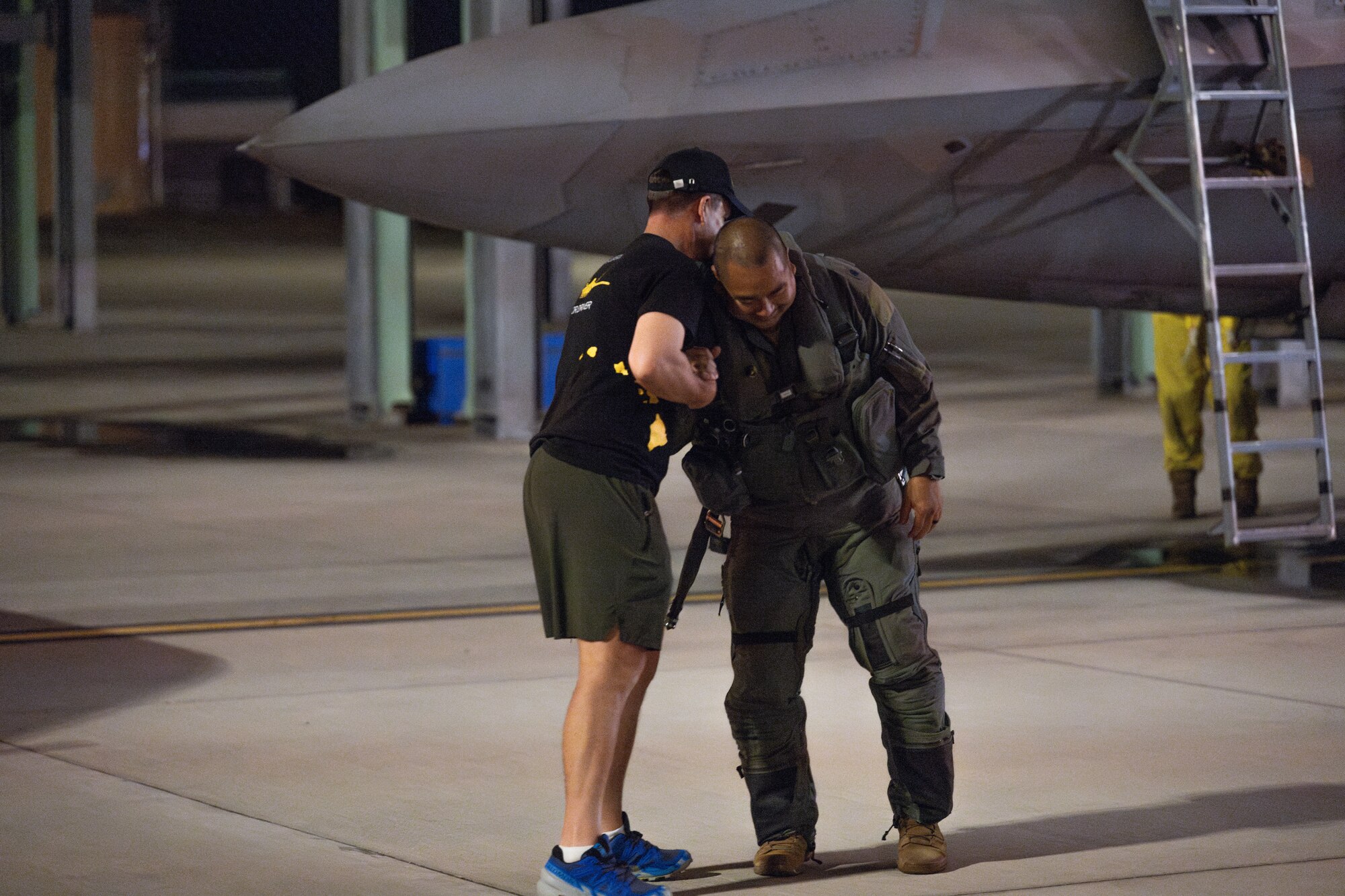 A pilot greets a friend in front of an aircraft.