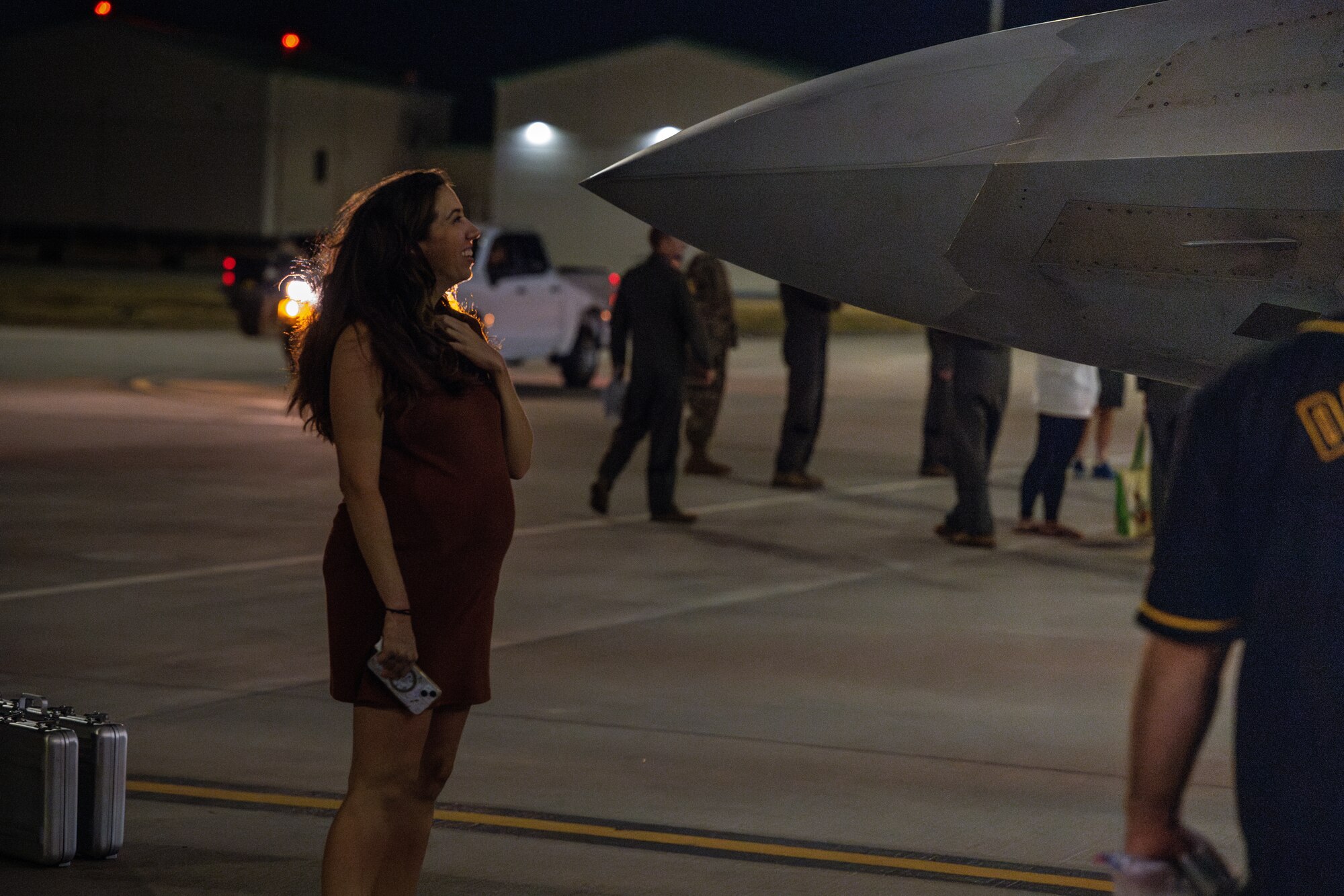 A spouse of a pilot waits in front of an aircraft.