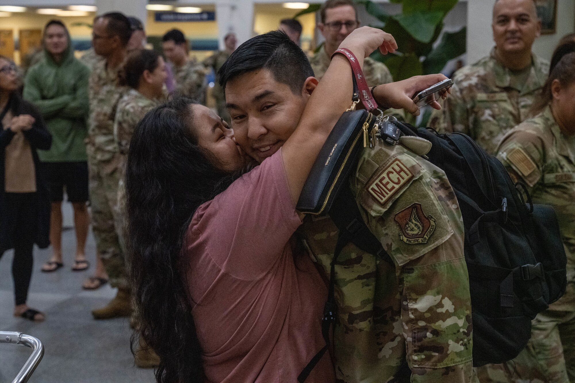 A U.S. Air Force Airman is greeted by a loved one with a hug.