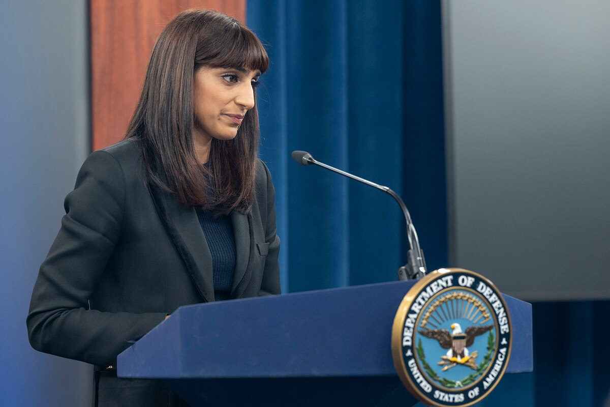 A person in business attire speaks from a lectern.