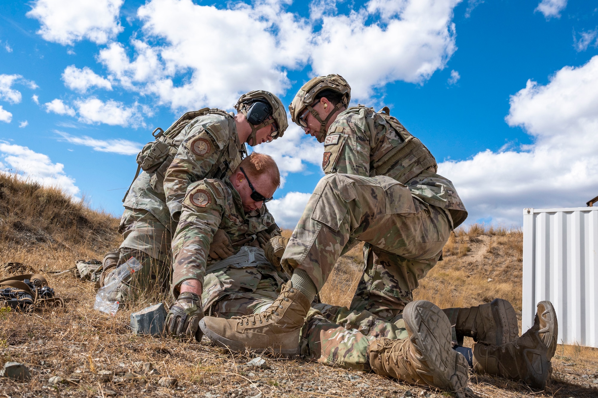 Two airmen performing life saving measures to another airman.