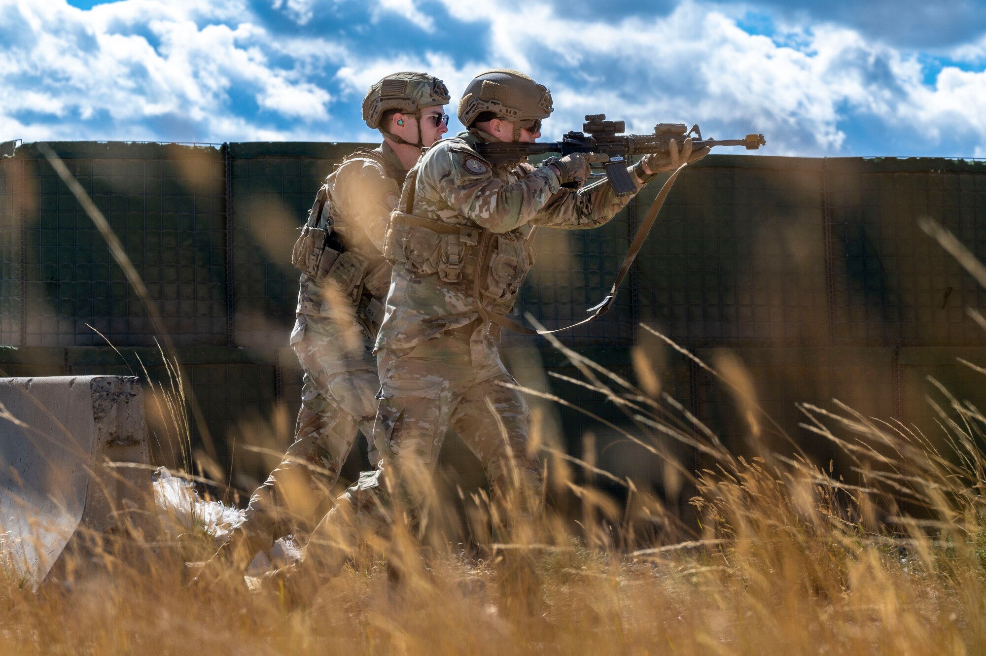 Two Airmen running while aiming their guns.