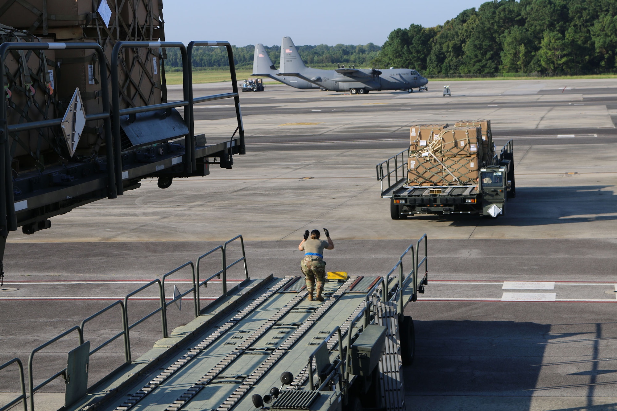 Senior Airman Georzena Sumang, 87th Aerial Port Squadron cargo representative, spots a Tunner 60K Loader into place as part of a cargo loading operation at Joint Base Charleston, S.C., Aug. 15, 2024. Airmen from the 87th APS and 437th APS staged cargo on three loaders assembled as a bridge and elevator.