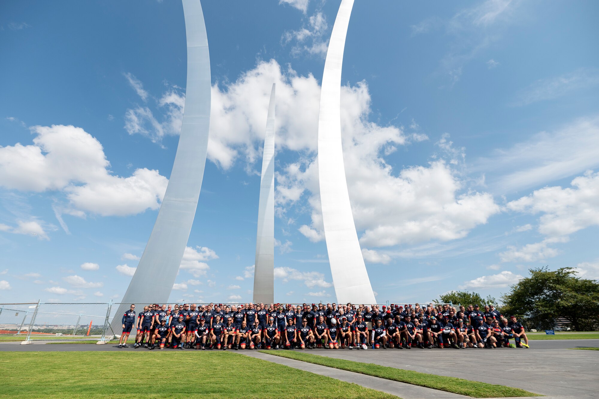 A large group of people take a photo near the Air Force Memorial.
