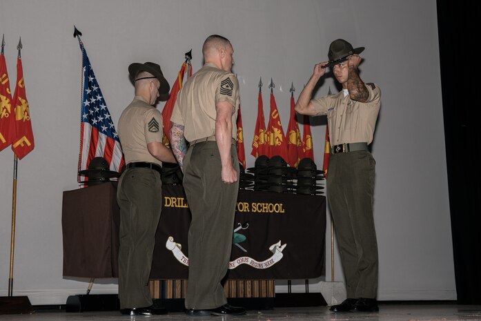 U.S. Marine Corps Sgt. Maj. Thomas J. Yeaman, left, the command senior enlisted leader, with Marine Fighter Attack Squadron 214, Marine Aircraft Group 13, 3rd Marine Aircraft Wing, gives Staff Sgt. Ivan Leonmunoz his campaign cover during the graduation ceremony for Drill Instructor School class 4-24 at Marine Corps Recruit Depot San Diego, California, Sept. 25, 2024. For the past 11 weeks the newly graduated drill instructors enhanced their leadership qualities, command presence, instructional ability, physical fitness and knowledge of selected officers and staff noncommissioned officers in order to successfully perform the duties of a drill instructor. The Marines will now go to their assigned Battalions at MCRD San Diego to train recruits for the remainder of their tour. (U.S. Marine Corps photo by Cpl. Sarah M. Grawcock)