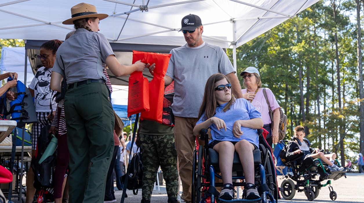 Park Ranger handing a life jacket to a family.