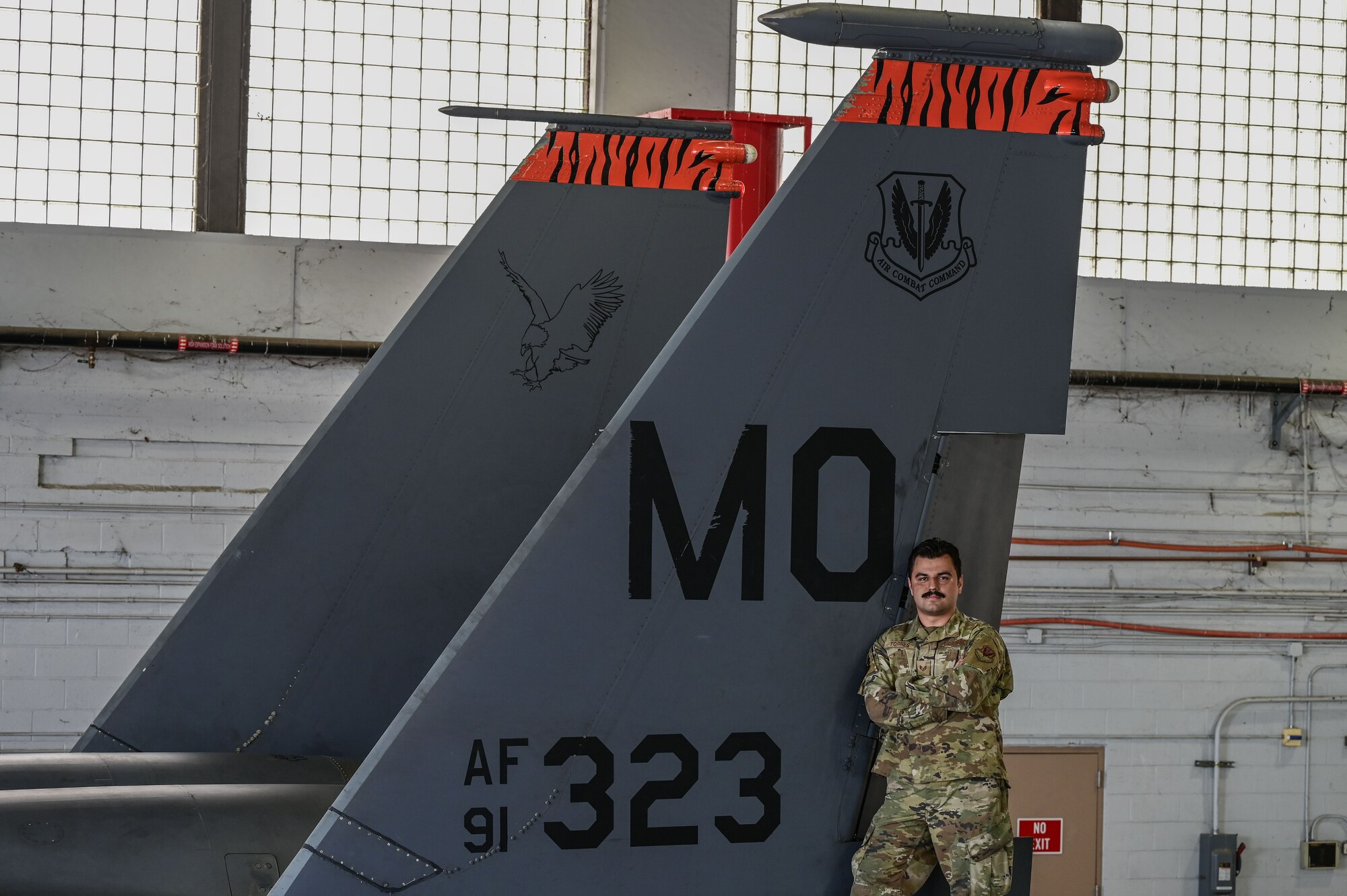 Airman poses in front of jet.