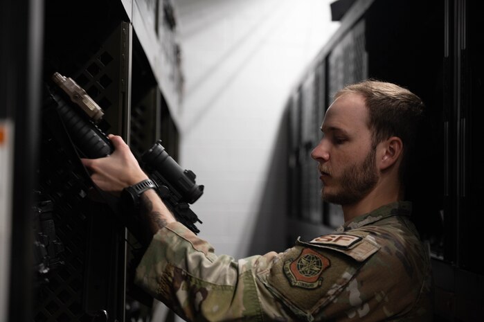 An armorer retrieves a rifle in an armory
