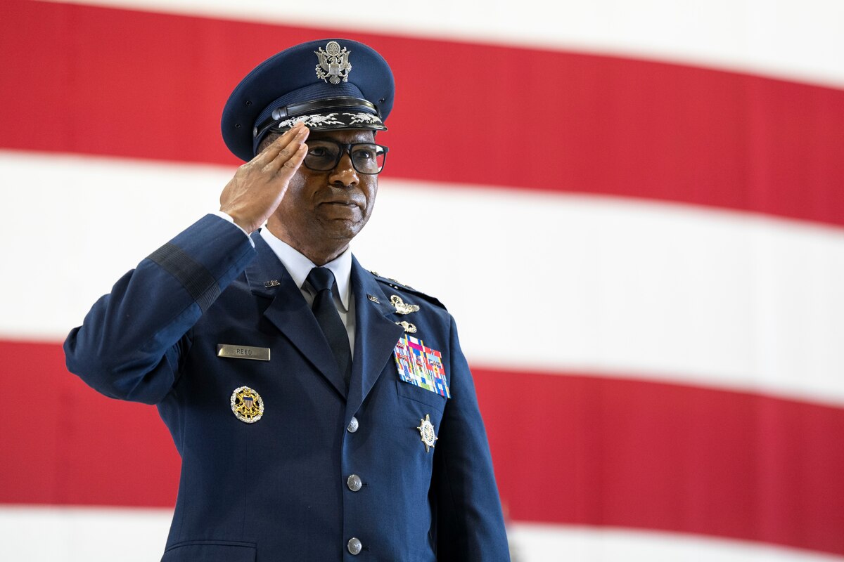 A man salutes while standing in front of an American flag.
