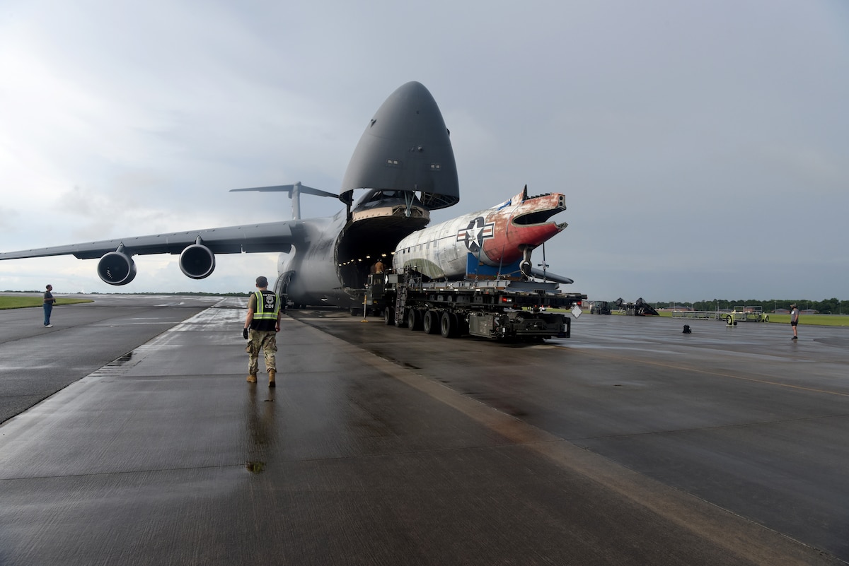 People unloading a smaller aircraft out of a large aircraft