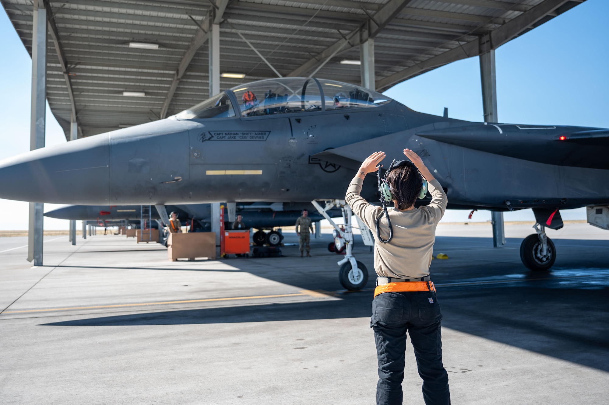 Airman stands in front of a jet.