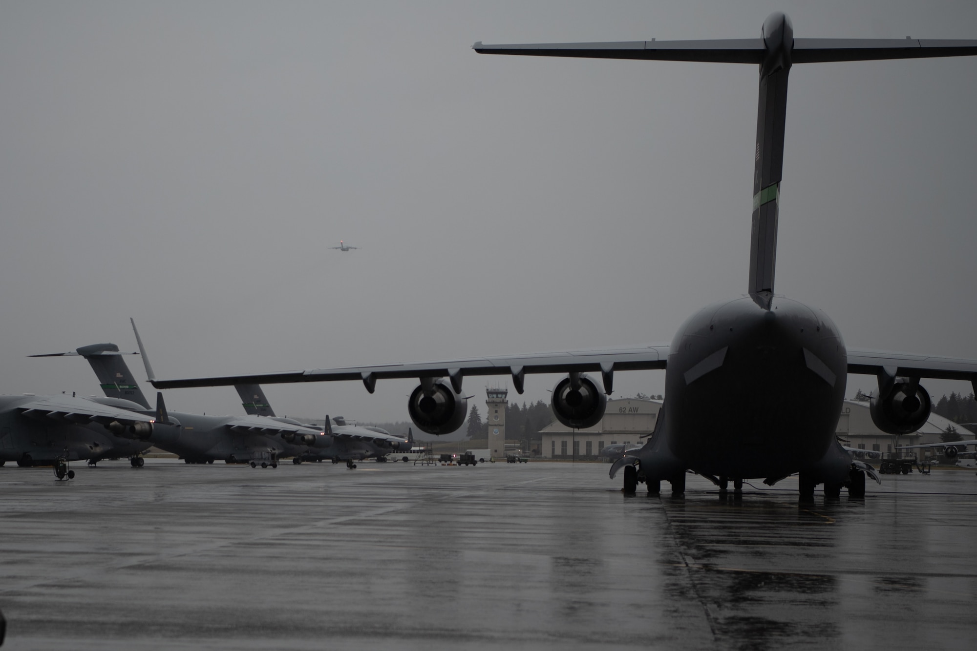 U.S. Air Force C-17 Globemaster III aircraft are seen on the Joint Base Lewis-McChord, Washington, flightline, with one aircraft in the air, conducting operations in support of Exercise Rainier War 25A, Oct. 4, 2024.