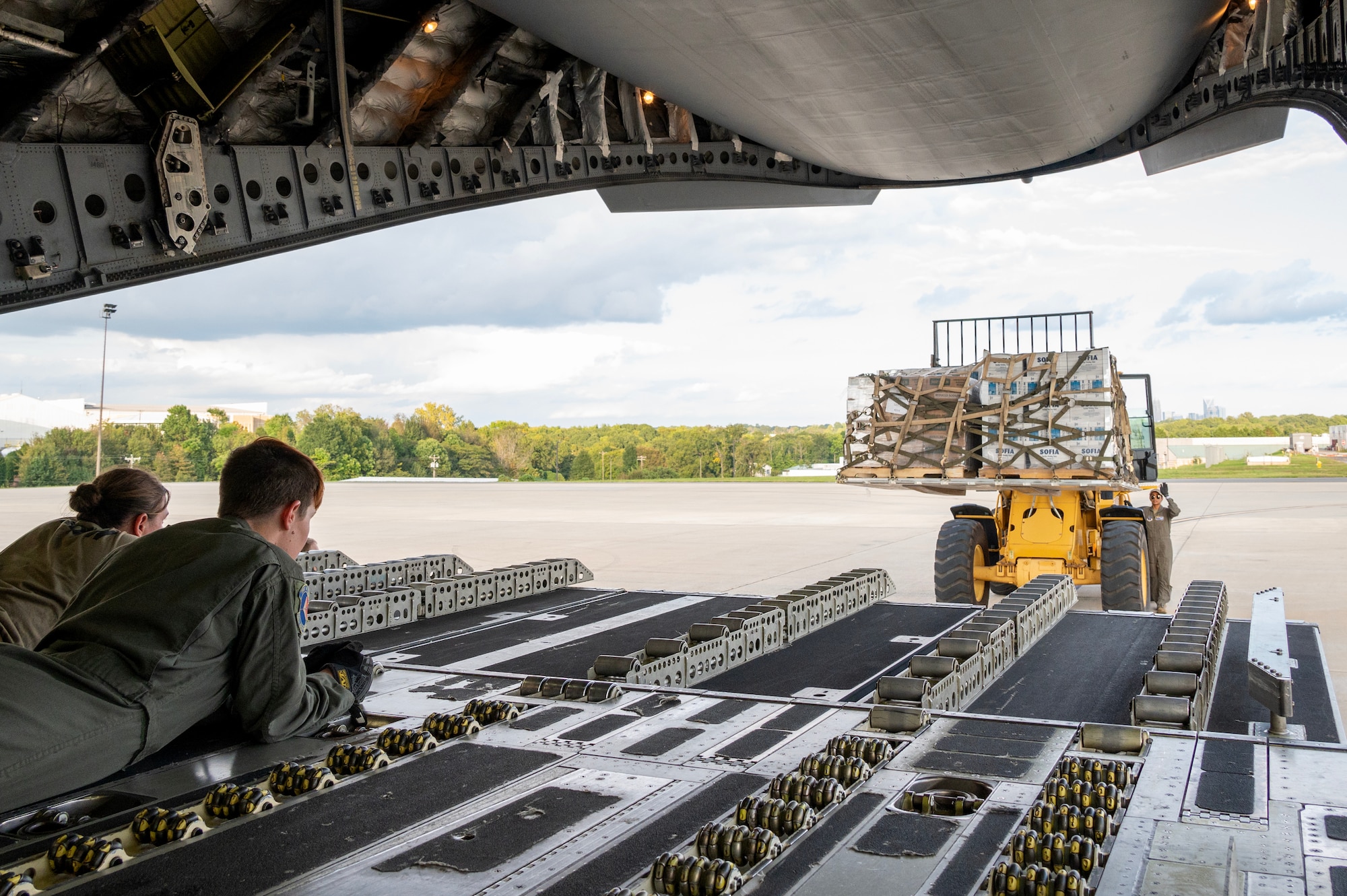 Senior Airman Rielly K. Coolidge, 156th Airlift Squadron loadmaster, left, and Master Sgt. Madeline D. Hefner,  156th Airlift Squadron loadmaster, middle, safety observe as Tech. Sgt. Kaushika P. Silva, 156th Airlift Squadron loadmaster, right, marshals a hurricane relief pallet to a C-17 Globemaster III for delivery to Western North Carolina in support of humanitarian efforts following Tropical Storm Helene at the North Carolina Charlotte-Douglas, International Airport, October 3, 2024. The cargo delivered aboard the C-17 consisted of Meals Ready to Eat (MREs), water, medication and other vital supplies. (U.S. Air National Guard photo by Staff Sgt. Reanna Hartgrove)