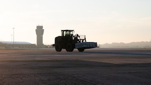 An airman operates a forklift on a flightline.