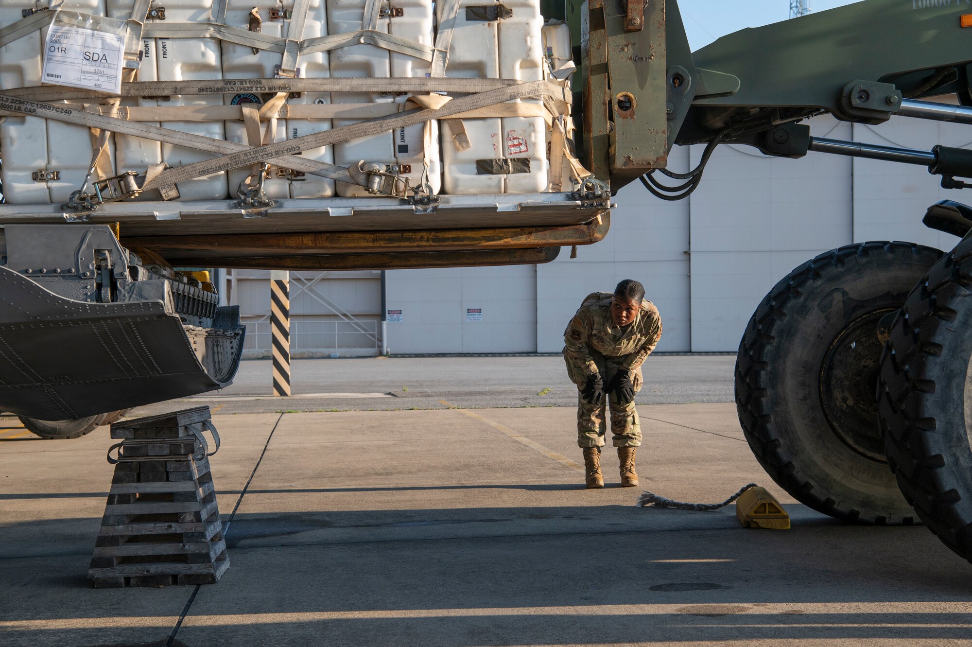 An airman checks if a forklift clears the aircraft floor.