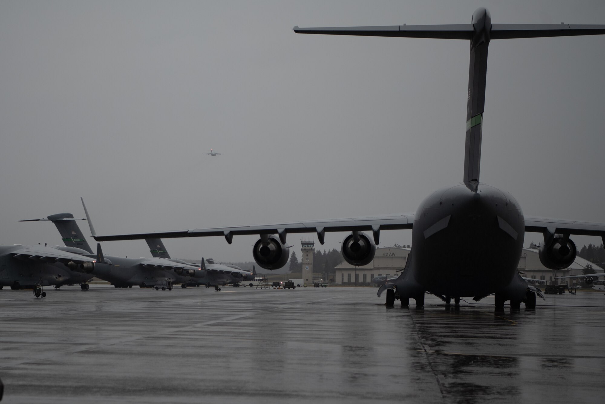 U.S. Air Force C-17 Globemaster III aircraft are seen on the Joint Base Lewis-McChord, Washington, flightline, with one aircraft in the air, conducting operations in support of Exercise Rainier War 25A, Oct. 4, 2024.