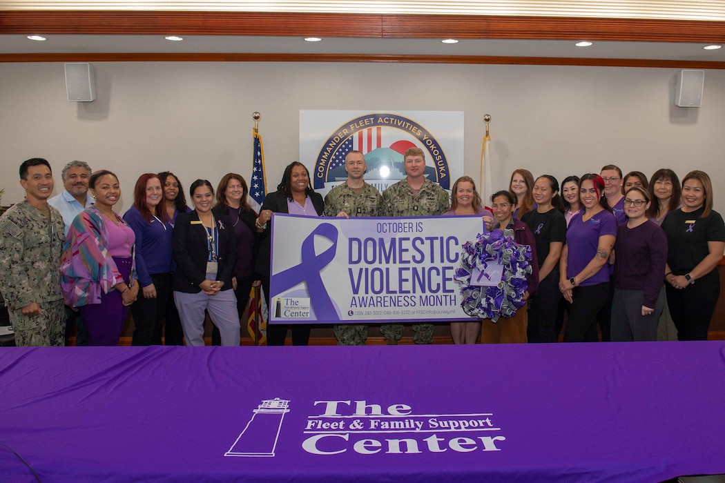 Command Master Chief Dennis Hunt, center left, and Master Chief Boatswain's Mate Jeffrey Brooks, center right, pose for a photo with employees and volunteers of the Fleet and Family Support Center (FFSC), during the FFSC Domestic Violence Proclamation Signing event for Domestic Violence Awareness Month at Commander, Fleet Activities Yokosuka’s headquarters.