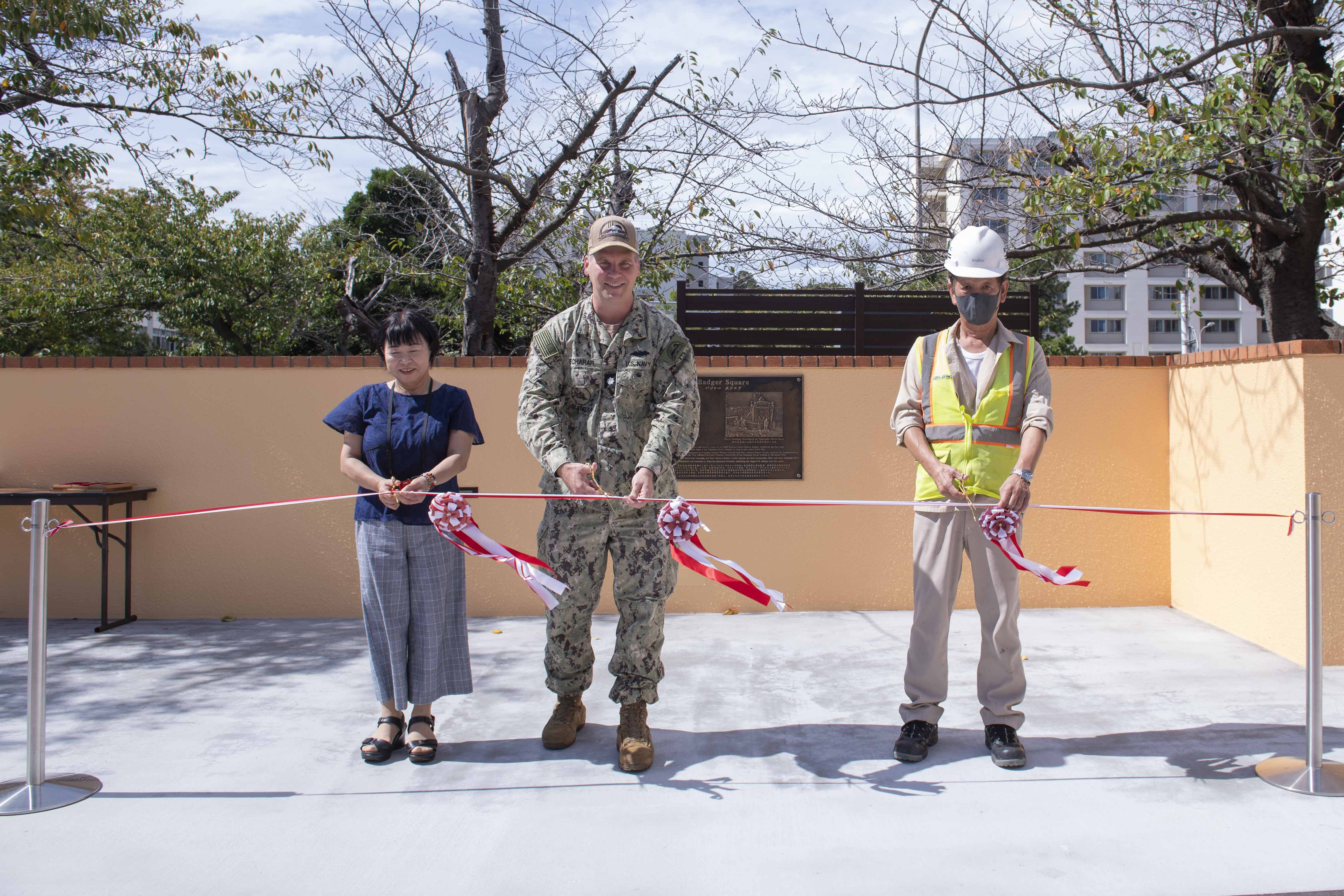 mdr. Tyler Scharer, public works officer for Commander, Fleet Activities Yokosuka (CFAY), center, cuts a ribbon during a ribbon-cutting ceremony celebrating the opening of Badger Square at the installation’s Kosano Park.
