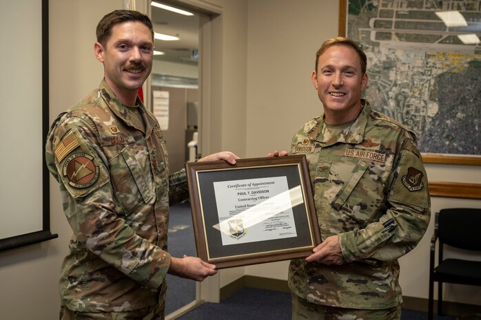 U.S. Air Force Maj. Matthew Bogan, right, 35th Contracting Squadron commander, presents U.S. Air Force Col. Paul Davidson, 35th Fighter Wing commander, a contracting officer certificate of appointment during the end of fiscal year closeout at Misawa Air Base, Japan, Sept. 30, 2024.