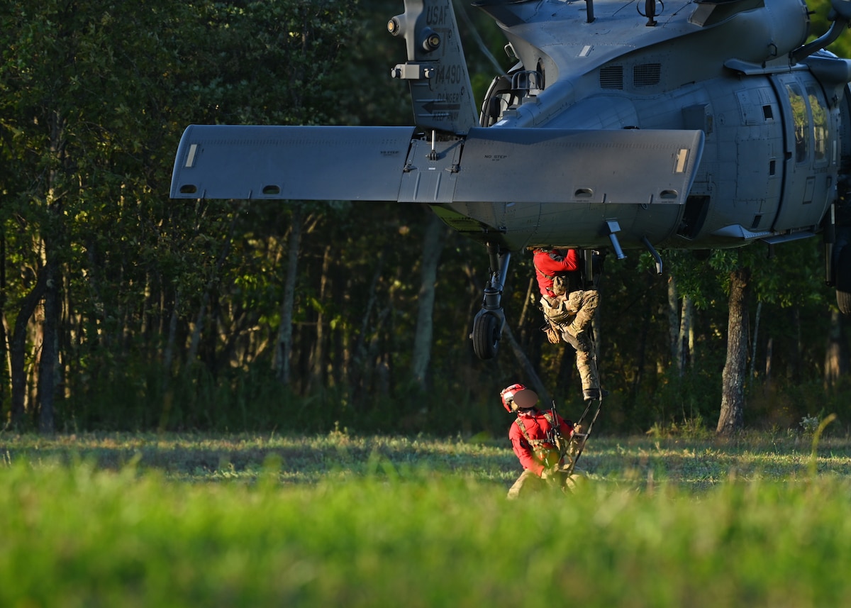 U.S. Airmen assigned to the 48th Rescue Squadron, forward deployed as the 563rd Personnel Recovery Task Force, climb a rope ladder into an HH-60W Jolly Green II helicopter in Tennessee, Oct. 2, 2024, in support of the U.S. Northern Command and Air Forces Northern, Defense Support of Civil Authorities Disaster Relief mission. The Department of Defense has unique capabilities, including an ability to deploy on short notice into austere environments, while providing resources that are not readily available in other federal agencies or the private sector. (U.S. Air Force photo by Staff Sgt. Abbey Rieves) (Note this photo has been altered for security purposes by blurring out facial identification.)