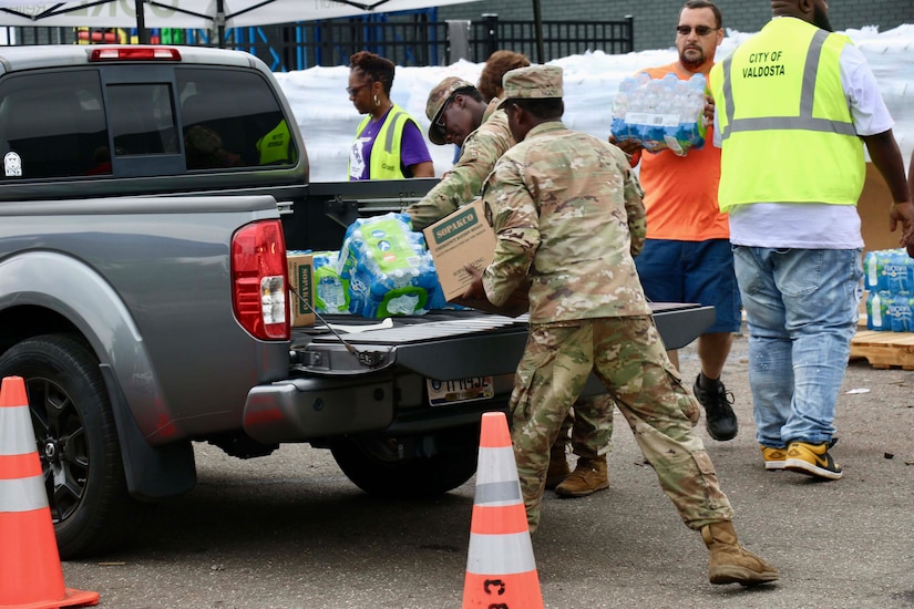 National Guardsmen load supplies on the back of a pickup truck.