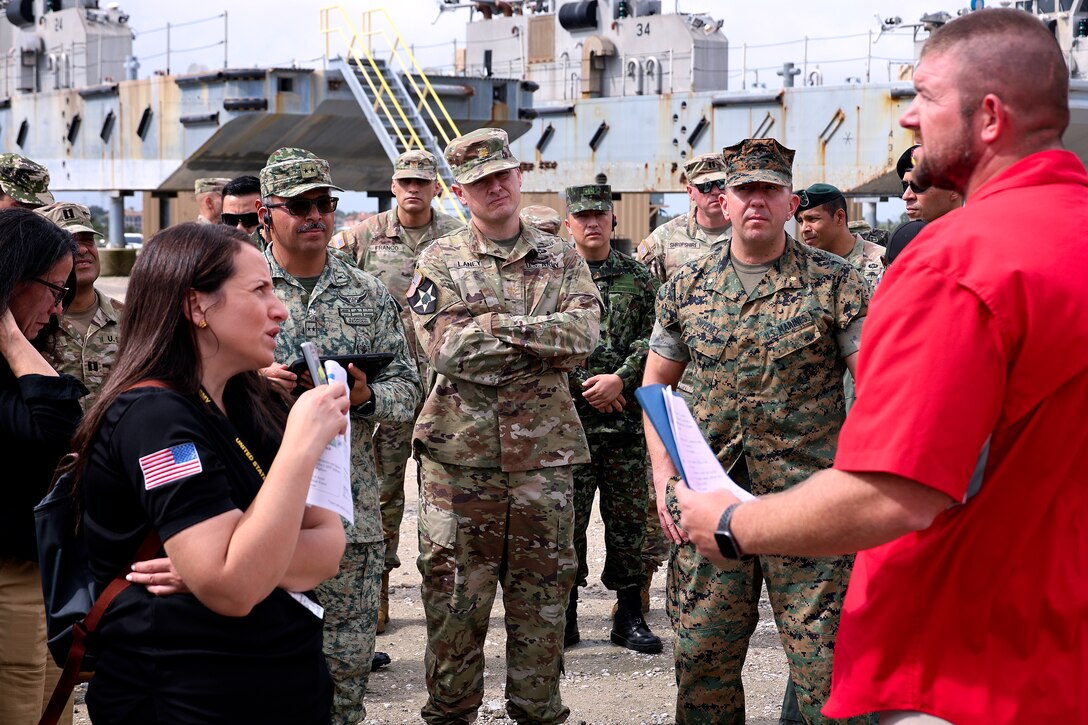 Students from Western Hemisphere Institute for Security Cooperation listen to Kevin McCandlish, Navy equipment specialist, Blount Island Command, explain maintenance and logistics oversight procedures during a tour Sept. 13, 2024, at Marine Corps Support Facility Blount Island in Florida. Of the nearly 60 students from the military education and training institute in Fort Moore, Georgia, roughly half were staff officers from a dozen partner nations spanning from Mexico through South America. After learning about military equipment and staging areas, the students toured USNS 1st Lt. Baldomero Lopez, a U.S. Navy roll-on, roll-off support cargo ship operated by Military Sealift Command. The 1,100-acre Marine Corps facility, located along the St. Johns River in northeast Florida, is the hub of Marine Corps’ prepositioning programs. Blount Island Command personnel—service members, government civilians and federal contractors—ensure Marines responding to global contingency areas are supported with the highest quality combat-ready equipment and supplies.