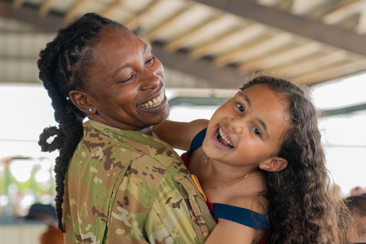 A close-up of a soldier smiling while holding a smiling loved one.