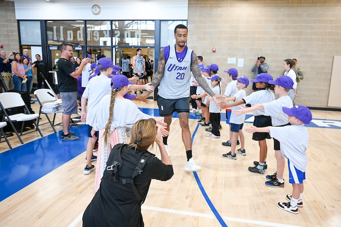 Collins high fives lines of children as he enters the basketball court.