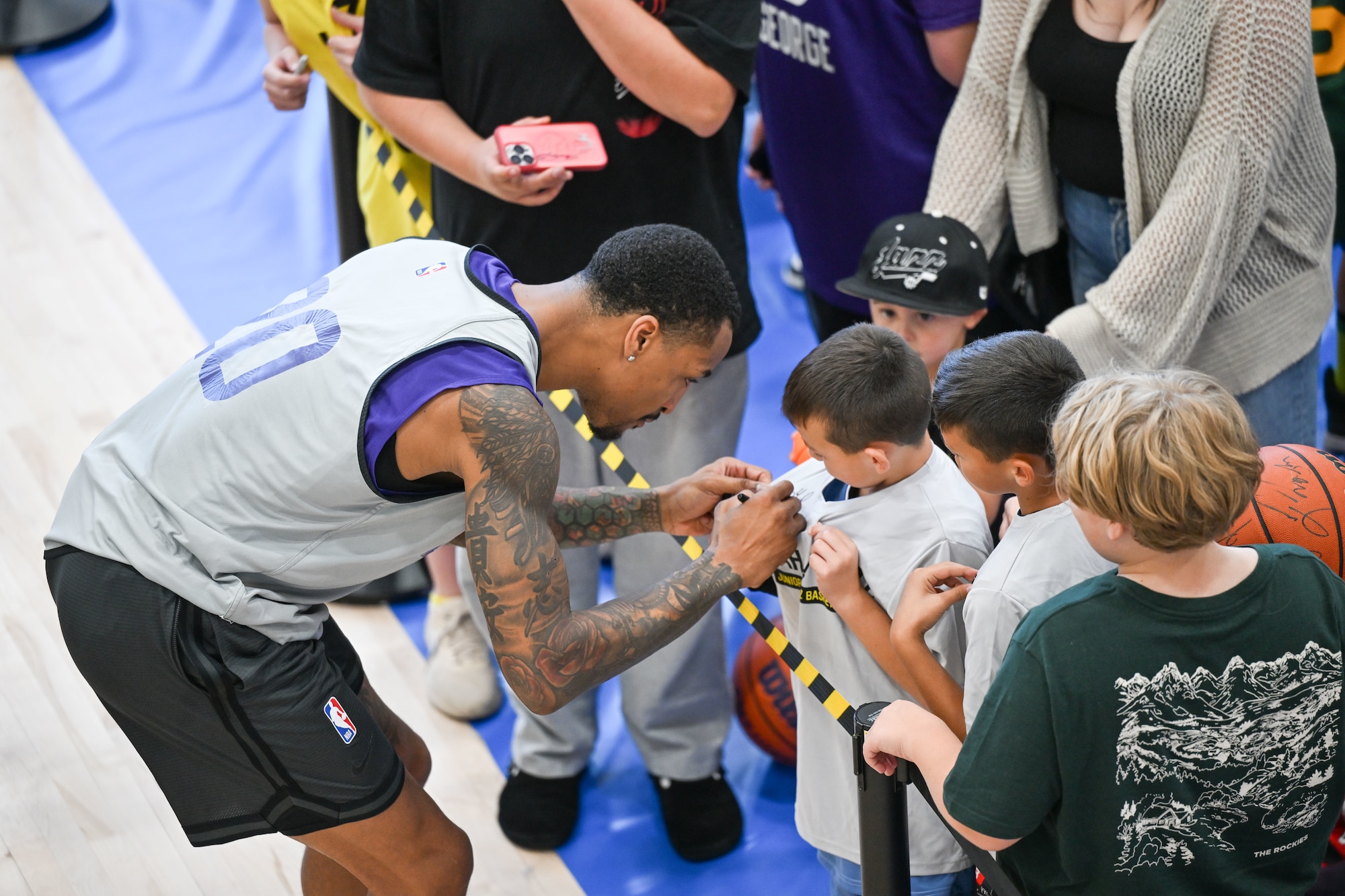 Collins signs his autograph on the t-shirt of a young fan.
