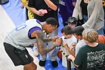 Collins signs his autograph on the t-shirt of a young fan.