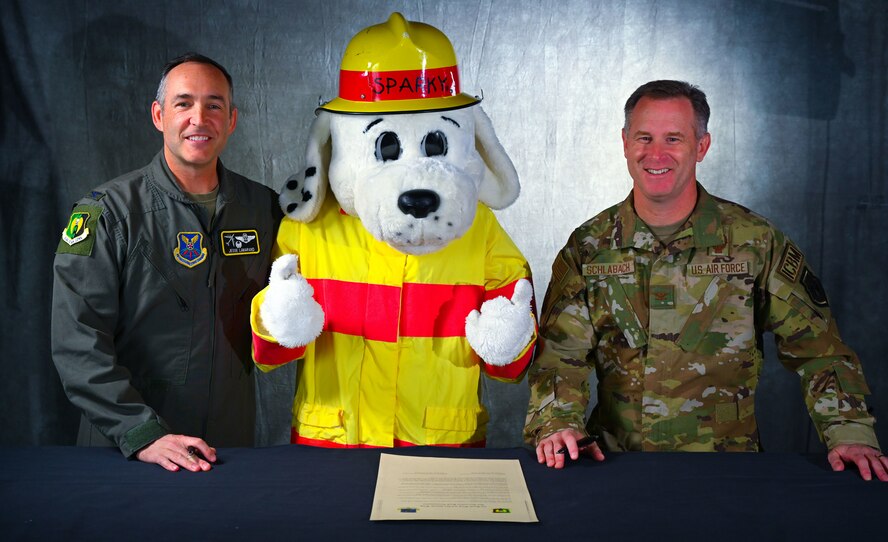 U.S. Air Force Col. Jesse Lamarand, 5th Bomb Wing (5 BW) commander (left), and Col. James Schlabach, 91st Missile Wing (91 MW) commander (right), pose for a photo with Sparky the Firedog for Fire Prevention Week on Sept. 30, 2024, Minot Air Force Base, North Dakota. Sparky was created for the National Fire Protection Association in 1951 to teach children and adults about fire safety.