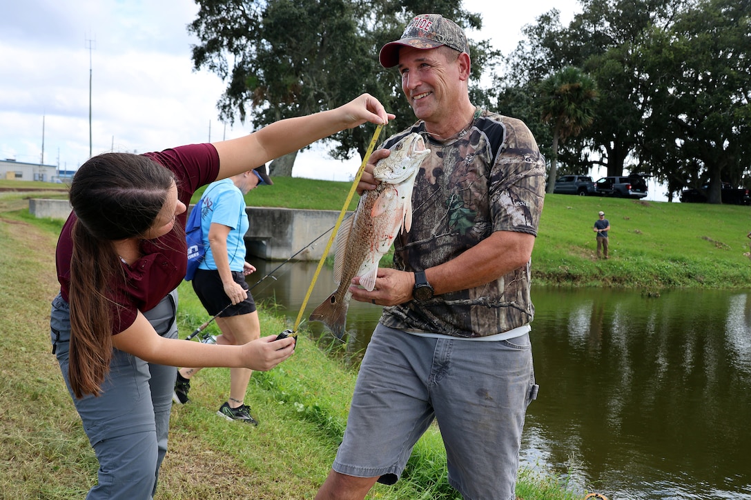 Taylor Comstock, Blount Island Command environmental protection specialist, measures a redfish caught by Bobby Carter, engineer equipment manager, during a quarterly catch-and-release tournament Oct. 3, 2024, at Marine Corps Support Facility Blount Island in Florida.