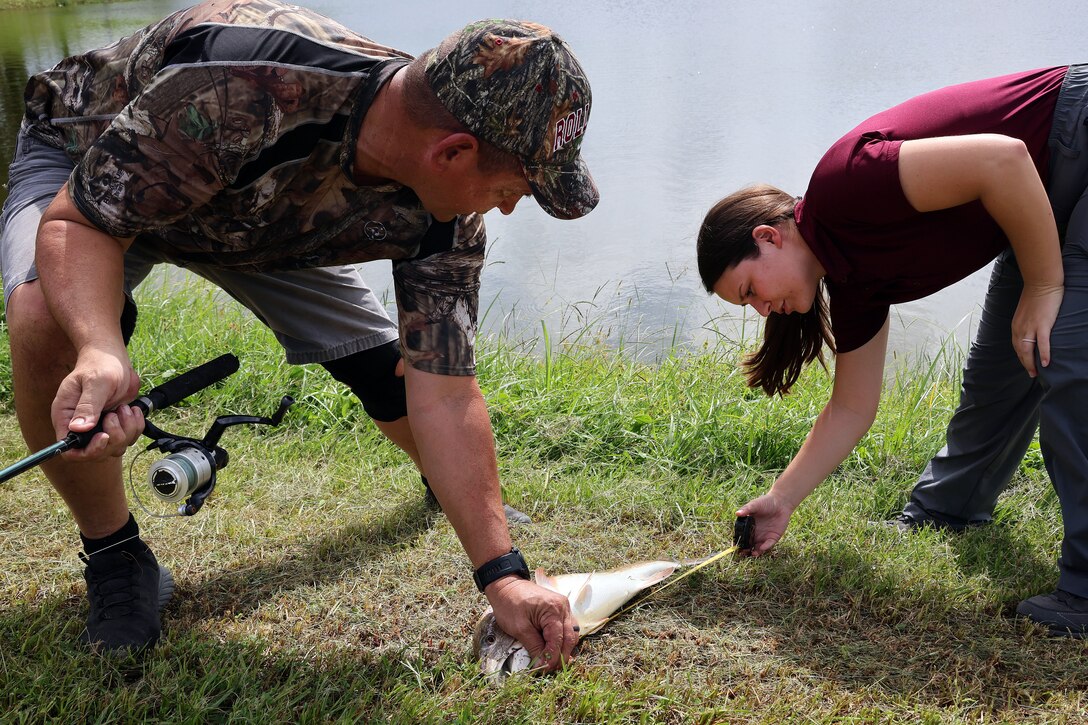 Bobby Carter, Blount Island Command engineer equipment manager, helps Taylor Comstock, environmental protection specialist, measure a redfish during a quarterly catch-and-release tournament Oct. 3, 2024, at Marine Corps Support Facility Blount Island in Florida.