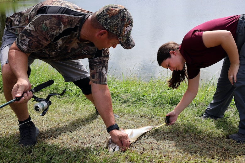 Bobby Carter, Blount Island Command engineer equipment manager, helps Taylor Comstock, environmental protection specialist, measure a redfish during a quarterly catch-and-release tournament Oct. 3, 2024, at Marine Corps Support Facility Blount Island in Florida.