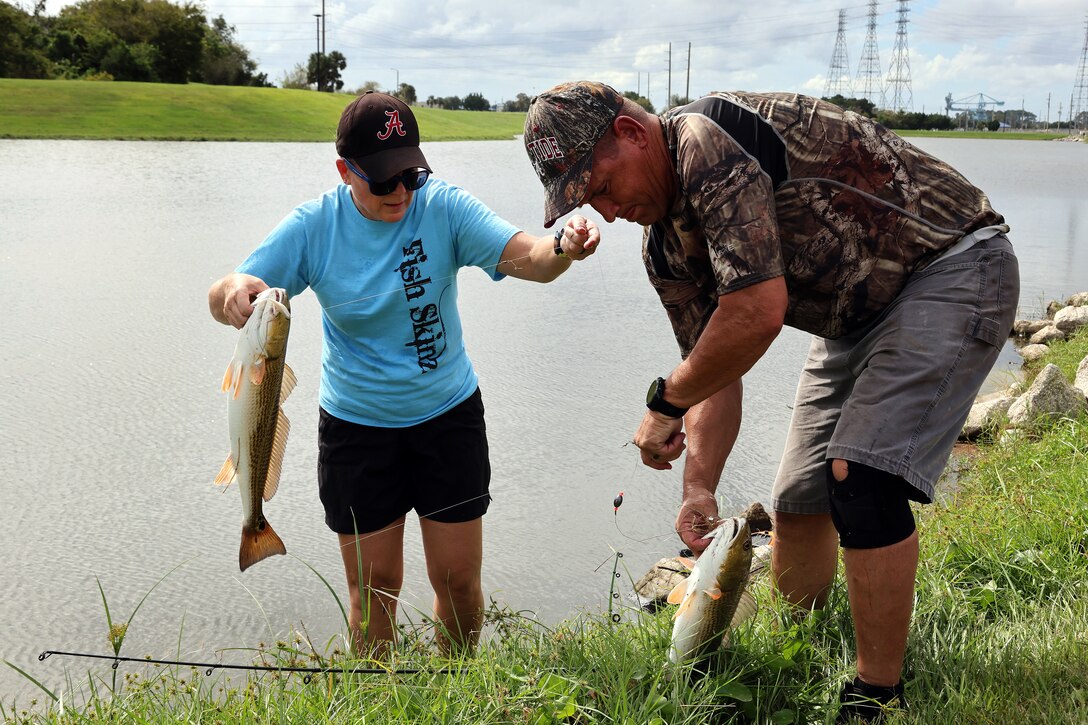 Frances Carter, Blount Island Command financial management analyst, lands a redfish with husband Bobby Carter, engineer equipment manager, during a quarterly catch-and-release tournament Oct. 3, 2024, at Marine Corps Support Facility Blount Island in Florida.