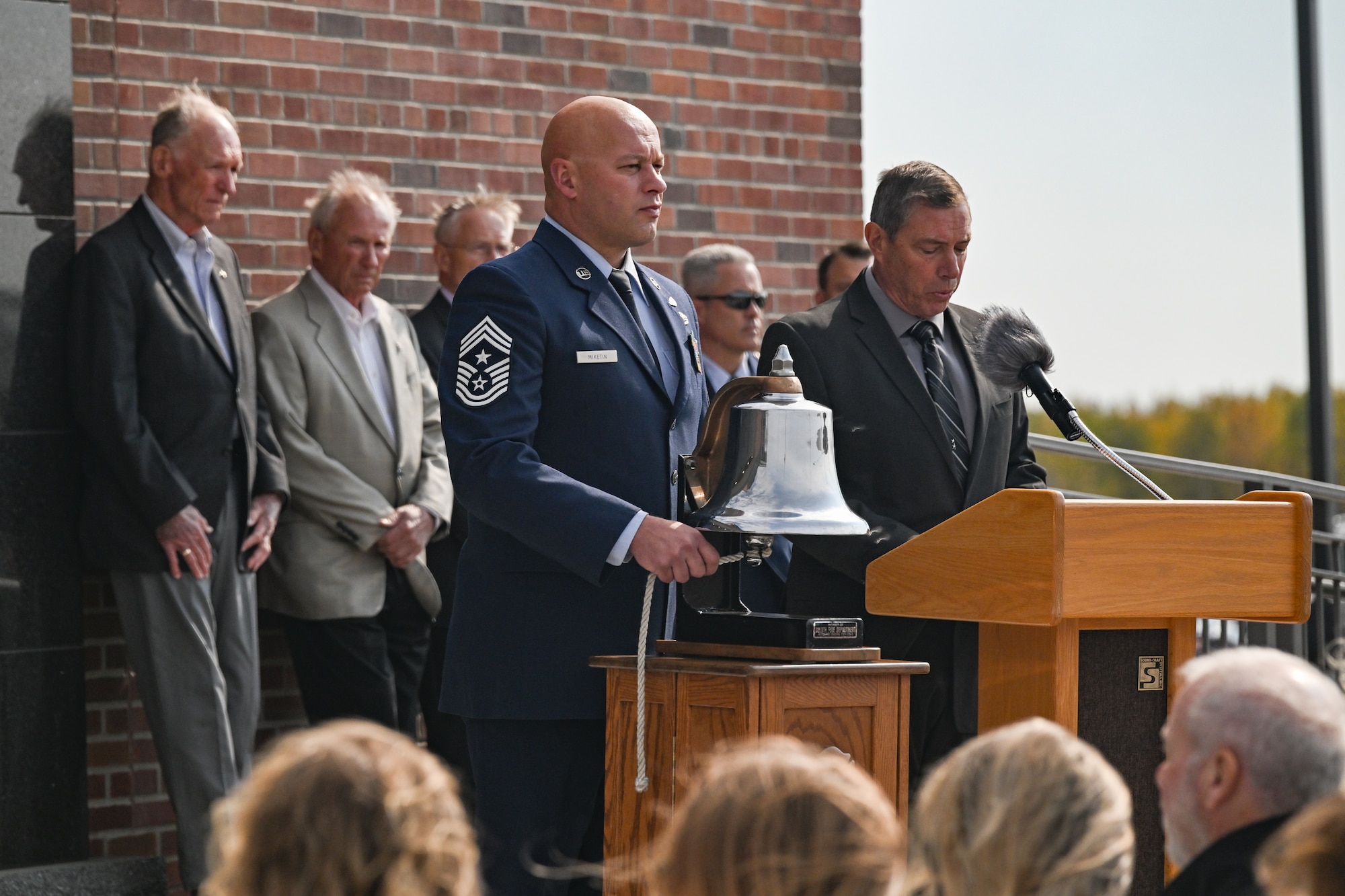 Retired Maj. Gen. Frank Stokes reads the names of fallen service members while 148th Fighter Wing Command Chief, Chief Master Sgt. Chief Jozef Miketin tolls the honor bell during the memorial wall dedication ceremony at the 148th Fighter Wing, in Duluth, Minn. Oct. 5, 2024. The newly completed memorial wall honors 21 fallen service members who were lost while conducting their military duties over the wing’s 76-year history. (U.S. Air National Guard photo by Staff. Sgt. Tylin Rust)