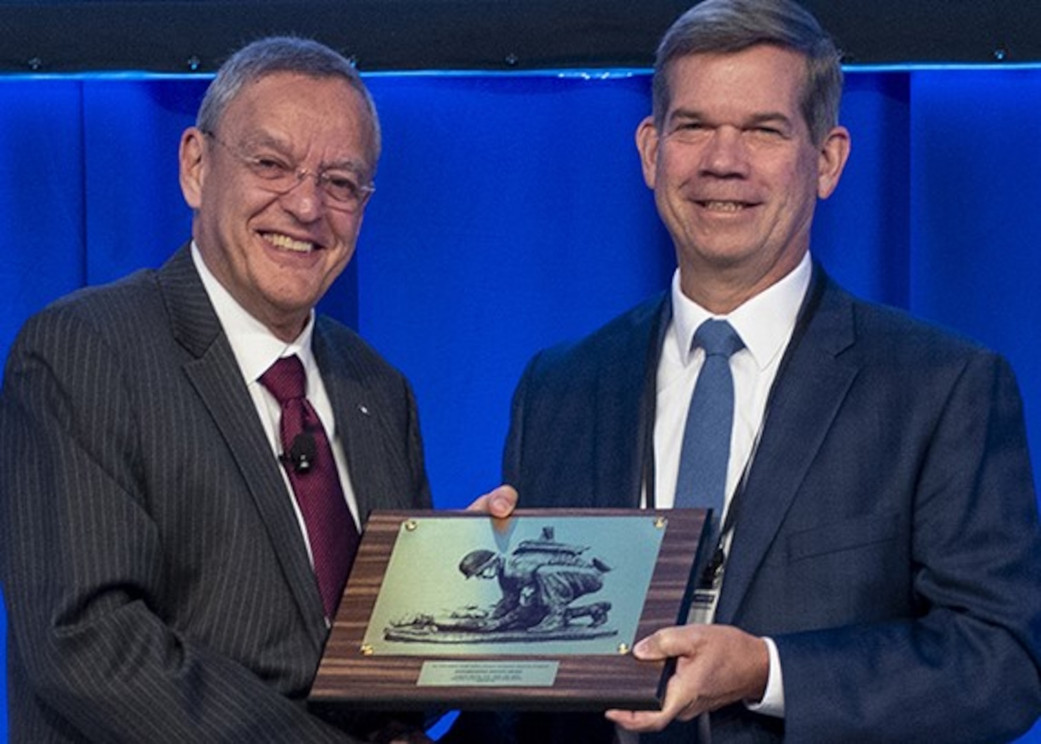 Dr. Lester Martínez López (left), the Assistant Secretary of Defense for Health Affairs, presents retired U.S. Army Col. (Dr.) Craig Shriver, director of the John P. Murtha Cancer Center at Walter Reed, with the Distinguished Service Award at the 2024 Military Health System Research Symposium.