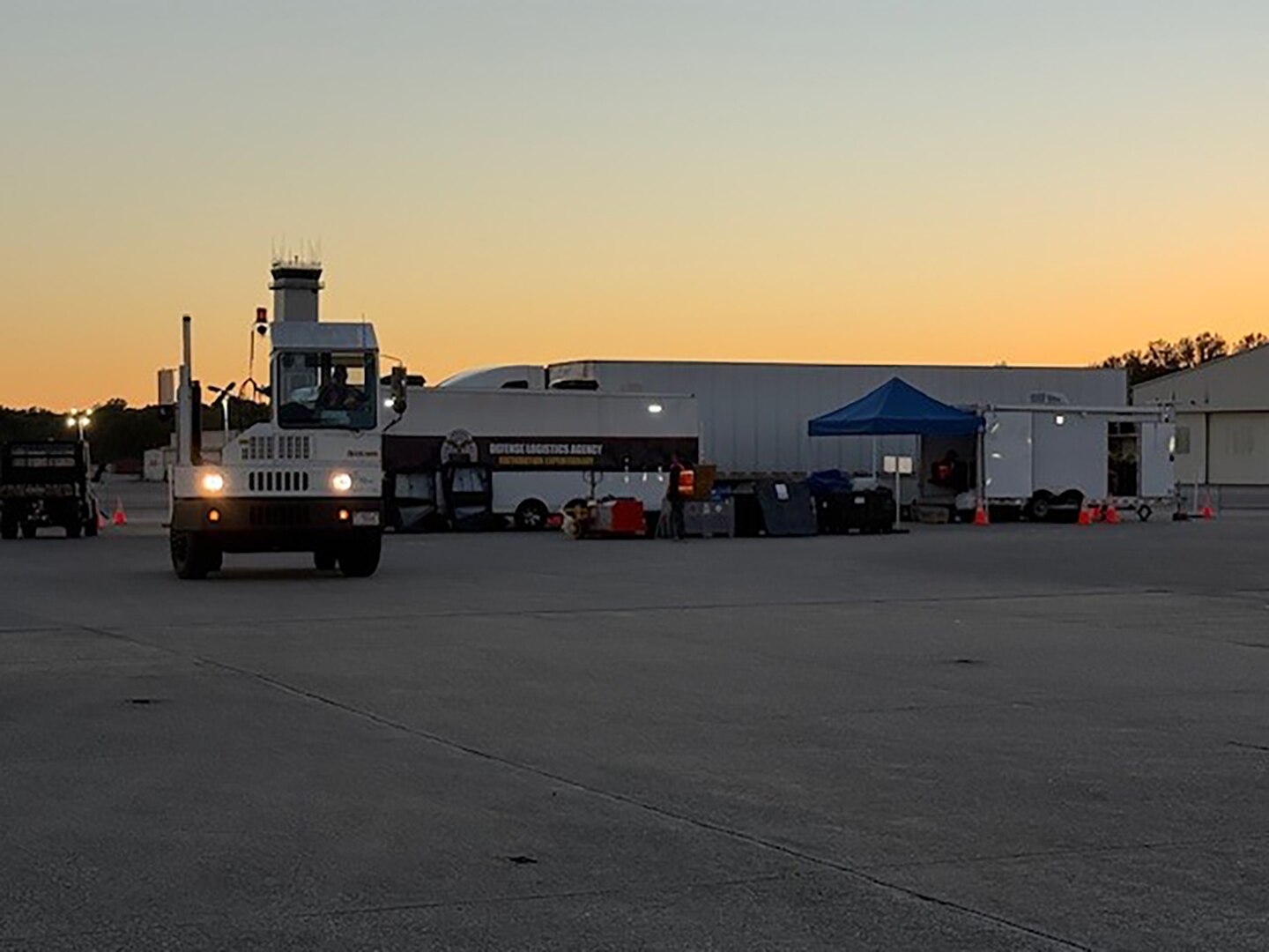 Trucks move in a parking lot outside at dusk