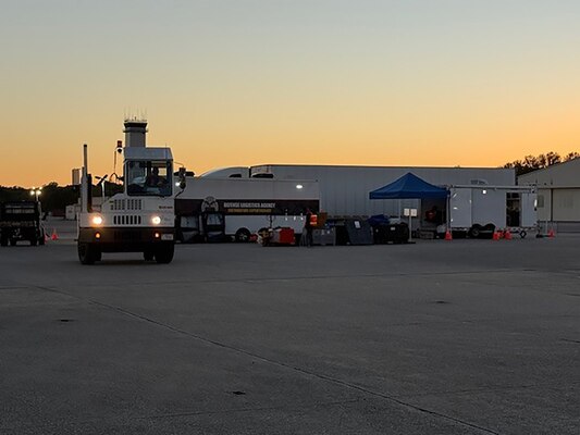 Trucks move in a parking lot outside at dusk